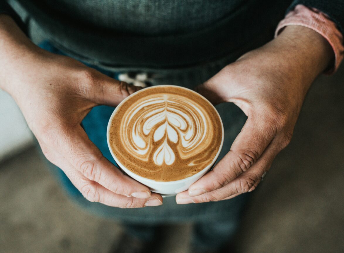 Kaffe Cappuccino som hålls upp med två händer