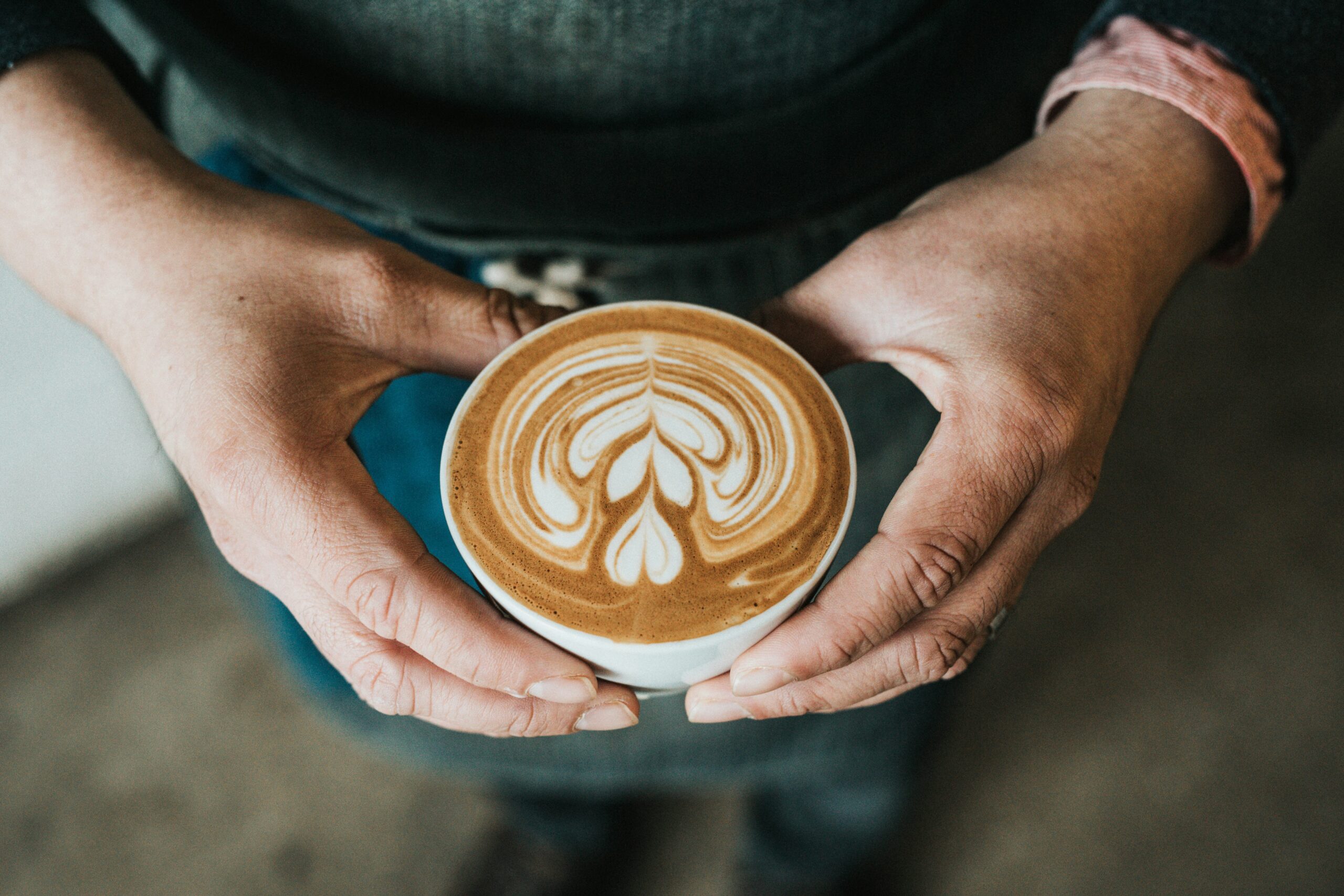 Kaffe Cappuccino som hålls upp med två händer